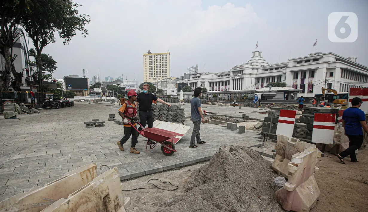 Pekerja menyelesaikan proyek revitalisasi di depan Stasiun Jakarta Kota, kawasan Kota Tua, Jakarta, Sabtu (23/7/2022). Pemprov DKI Jakarta menyatakan program revitalisasi di kawasan Kota Tua salah satunya bertujuan untuk meningkatkan aksesibilitas dengan mengintegrasikan beragam moda transportasi seperti kereta api, MRT, Transjakarta hingga angkutan perkotaan. (Liputan6.com/Faizal Fanani)