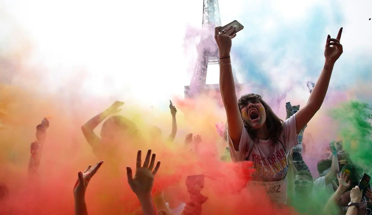 Ekspresi seorang wanita saat merayakan akhir perlombaan Color Run 2018 di depan Menara Eiffel di Paris, Prancis (15/4). Acara lari 5 kilometer ini diakhiri dengan saling lempar bubuk berwarna antar peserta. (AP/Thibault Camus)