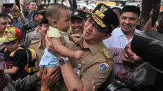 Gubernur DKI Jakarta Basuki T Purnama menggendong seorang anak balita di Tanah Abang, Jakarta, Rabu (15/4). Ahok berjalan kaki dari Stasiun Tanah Abang menuju Pasar Blok G untuk mengecek kondisi trotoar jalan. (Liputan6.com/Herman Zakharia)