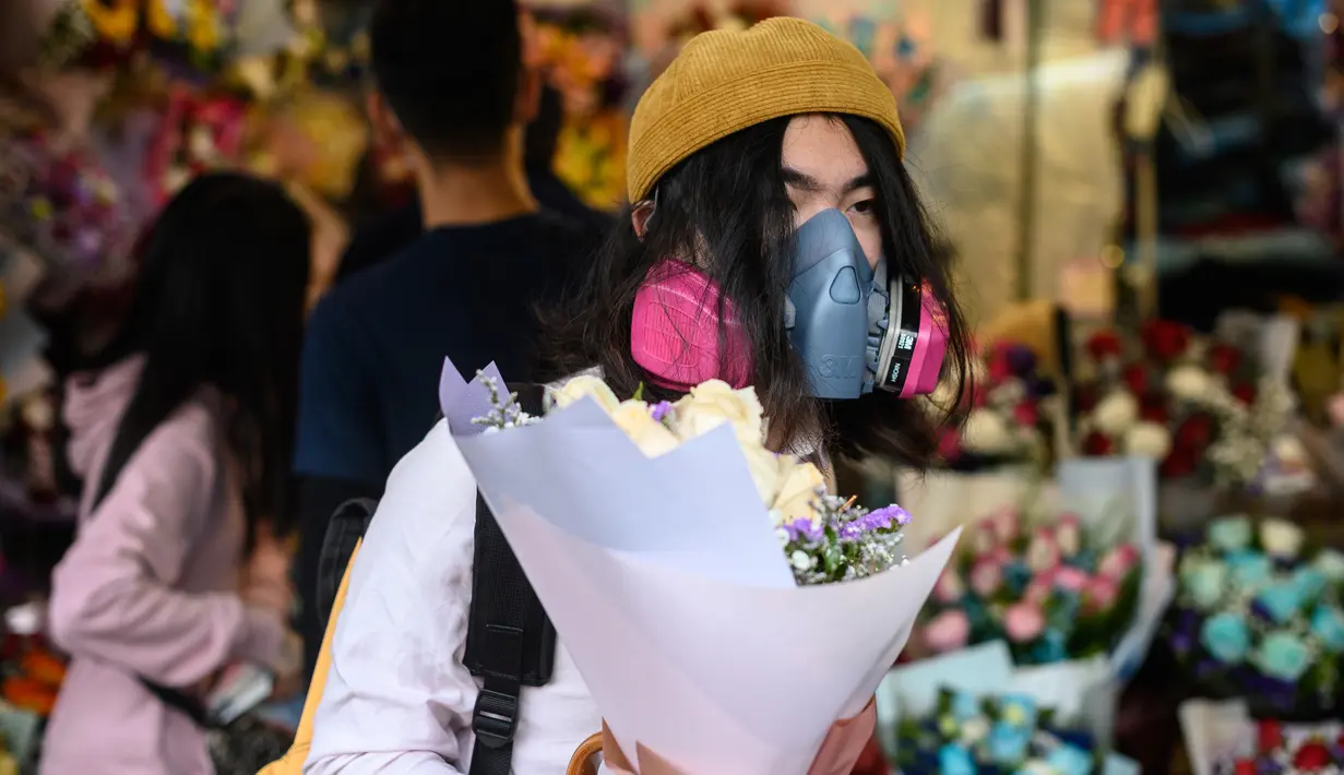 Seorang pria mengenakan masker pelindung sebagai tindakan pencegahan terhadap virus corona COVID-19, membeli bunga untuk menandai Hari Valentine di Hong Kong (14/2/2020). (AFP Photo/Philip Fong)