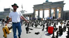 Seorang peternak sapi perah menyebarkan sepatu boots selama aksi protes di depan gerbang Brandenburg, Berlin, Jerman, Senin (30/5).  Mereka menuntut harga produk susu yang lebih adil bagi para peternak. (REUTERS/Fabrizio Bensch)