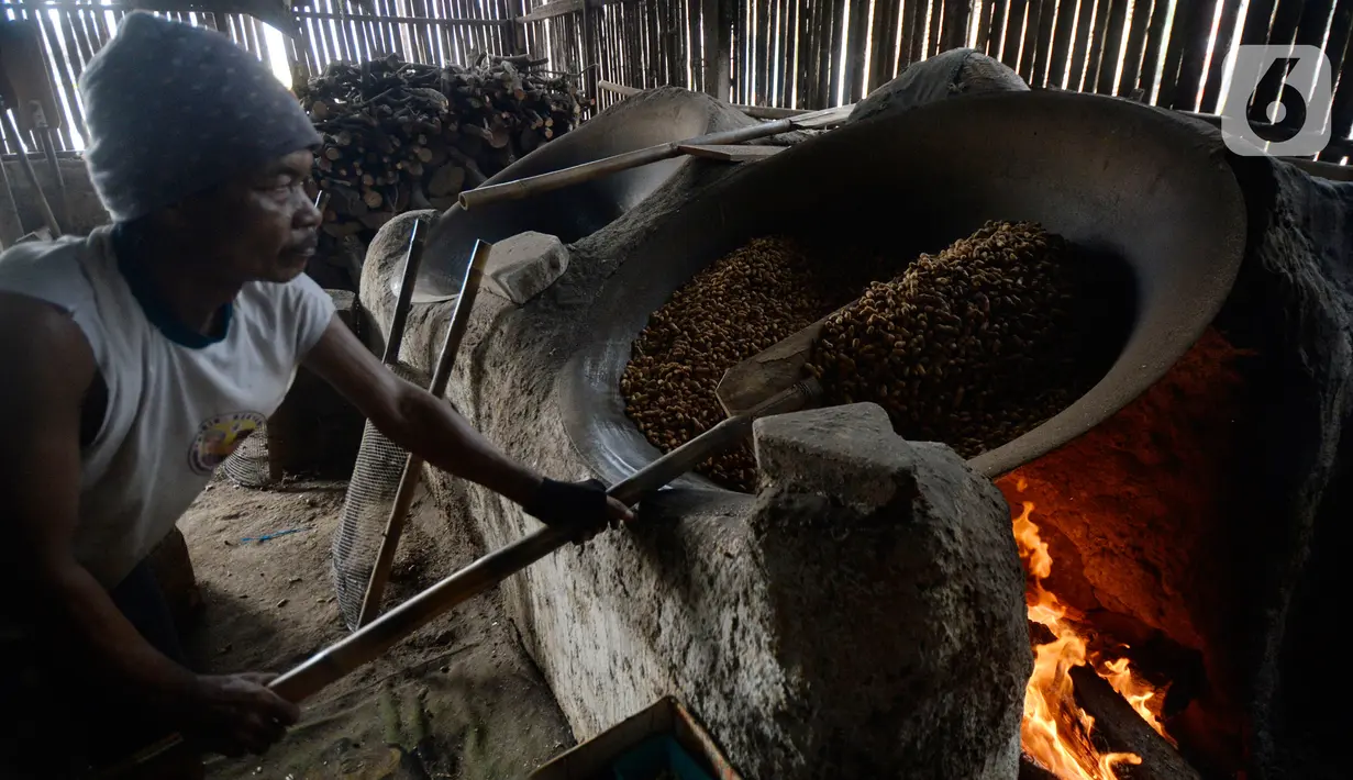 Pekerja mengolah kacang dengan media pasir di salah satu industri rumahan pembuatan kacang sangrai di Kawasan Keranggan, Tangerang Selatan, Selasa (11/8/2020). Kacang sangrai yang dipasarkan seharga Rp10.000 per kg itu mulai mengalami kenaikan pesanan dibanding bulan lalu. (merdeka.com/Dwi Narwoko)