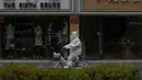 <p>Pekerja dengan APD mengendarai sepeda melewati toko-toko ritel yang tutup setelah pihak berwenang memerintahkan penutupan bisnis yang tidak penting dan meminta orang untuk bekerja di rumah di distrik Chaoyang, Beijing, Senin (9/5/2022). Jutaan orang di Beijing tinggal di rumah pada 9 Mei ketika ibu kota China mencoba untuk menangkis Covid -19 wabah dengan pembatasan ruang gerak. (AP Photo/Andy Wong)</p>