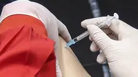 Vaksinator menyuntikkan vaksin COVID-19 dosis pertama produksi Sinovac kepada tenaga kesehatan saat vaksinasi massal di Istora Senayan, Jakarta, Kamis (4/2/2021). Rencananya, sekitar enam ribu tenaga kesehatan akan mengikuti vaksinasi COVID-19 dosis pertama tersebut. (Liputan6.com/Johan Tallo)