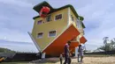 Orang-orang berjalan di luar rumah terbalik, di Guatavita, dekat Bogota, pada 29 Januari 2022. Rumah itu dirancang oleh pemiliknya, Fritz Schall dari Austria, yang tinggal di Kolombia. (Juan BARRETO / AFP)