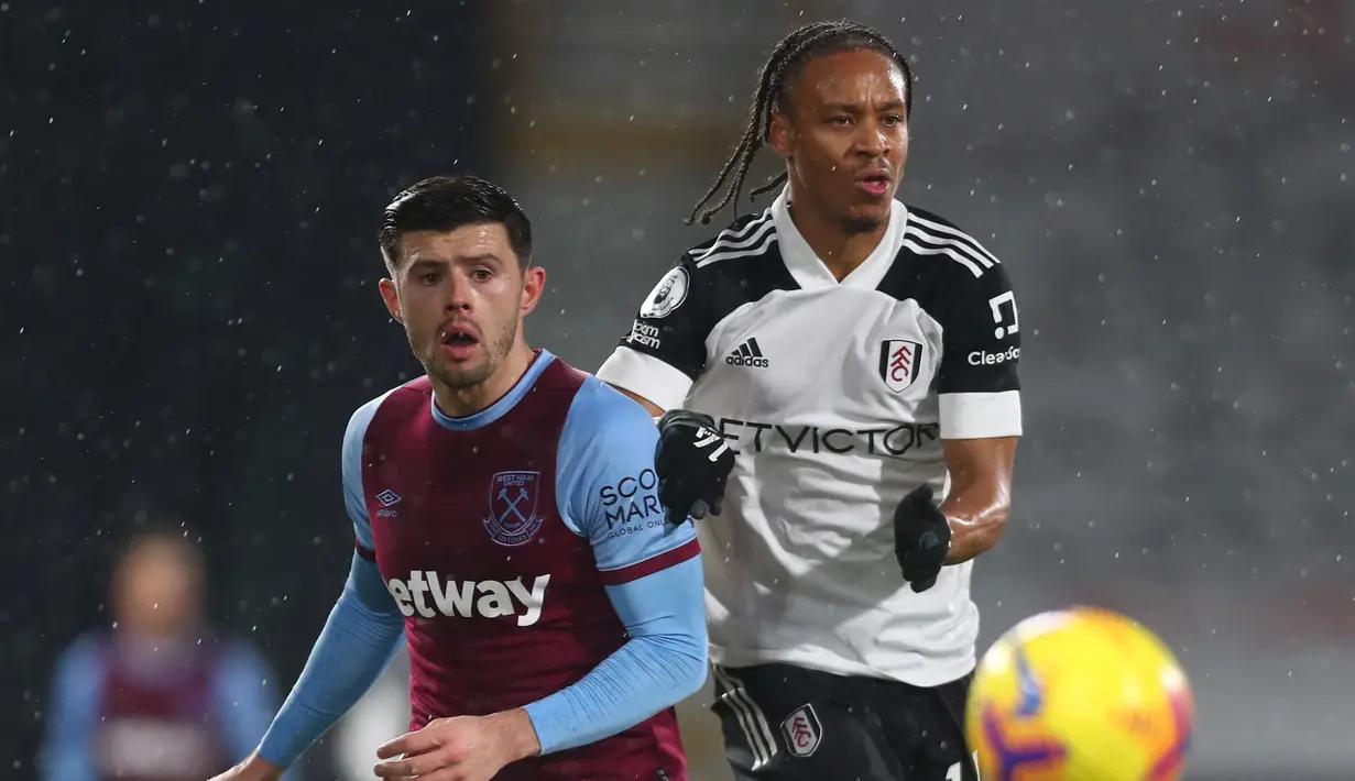Bek West Ham United, Aaron Cresswell (kiri) berebut bola dengan striker Fulham, Bobby Decordova-Reid dalam laga lanjutan Liga Inggris 2020/21 pekan ke-23 di Craven Cottage, Sabtu (6/2/2021). West Ham United bermain imbang 0-0 dengan Fulham. (AFP/Clive Rose/Pool)