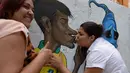 Dua orang wanita tampak berpose dengan karikatur Neymar, kota Rio de Janeiro, Jumat (9/5/2014) (AFP PHOTO / Vanderlei Almeida).