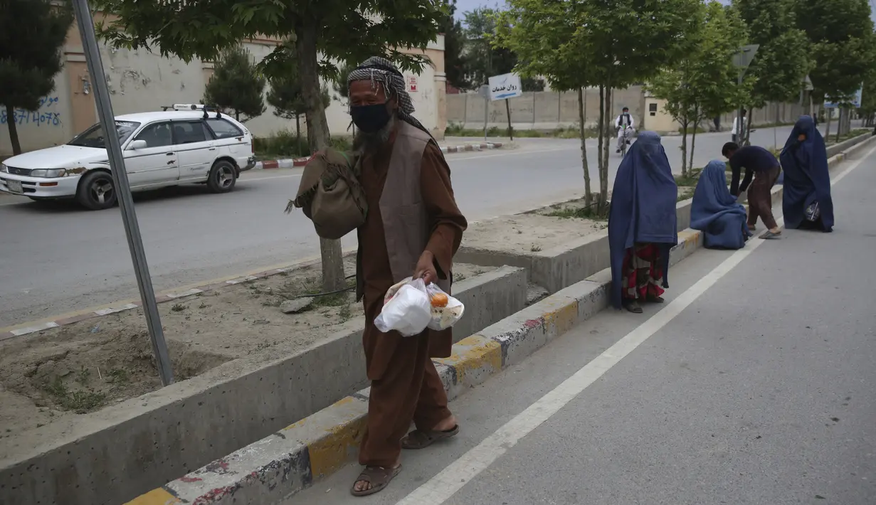 Warga membawa makanan berbuka puasa gratis yang disumbangkan oleh sukarelawan selama bulan puasa suci Ramadan di Kabul, Afghanistan, Kamis (7/5/2020). Muslim di seluruh dunia melewati Ramadan tahun ini di tengah pandemi virus corona COVID-19 dan PHK. (AP Photo/Rahmat Gul)