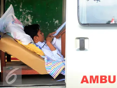 Seorang siswa SMP N 2 Pakem ,Fitrian (14) sedang mengerjakan soal Ujian Nasional di halaman SMP N 2 Pakem, Sleman, (10/5). Akibat kecelakaan,Fitrian terpaksa melaksanakan UN di dalam mobil ambulans . (Liputan6.com/Boy Harjanto)