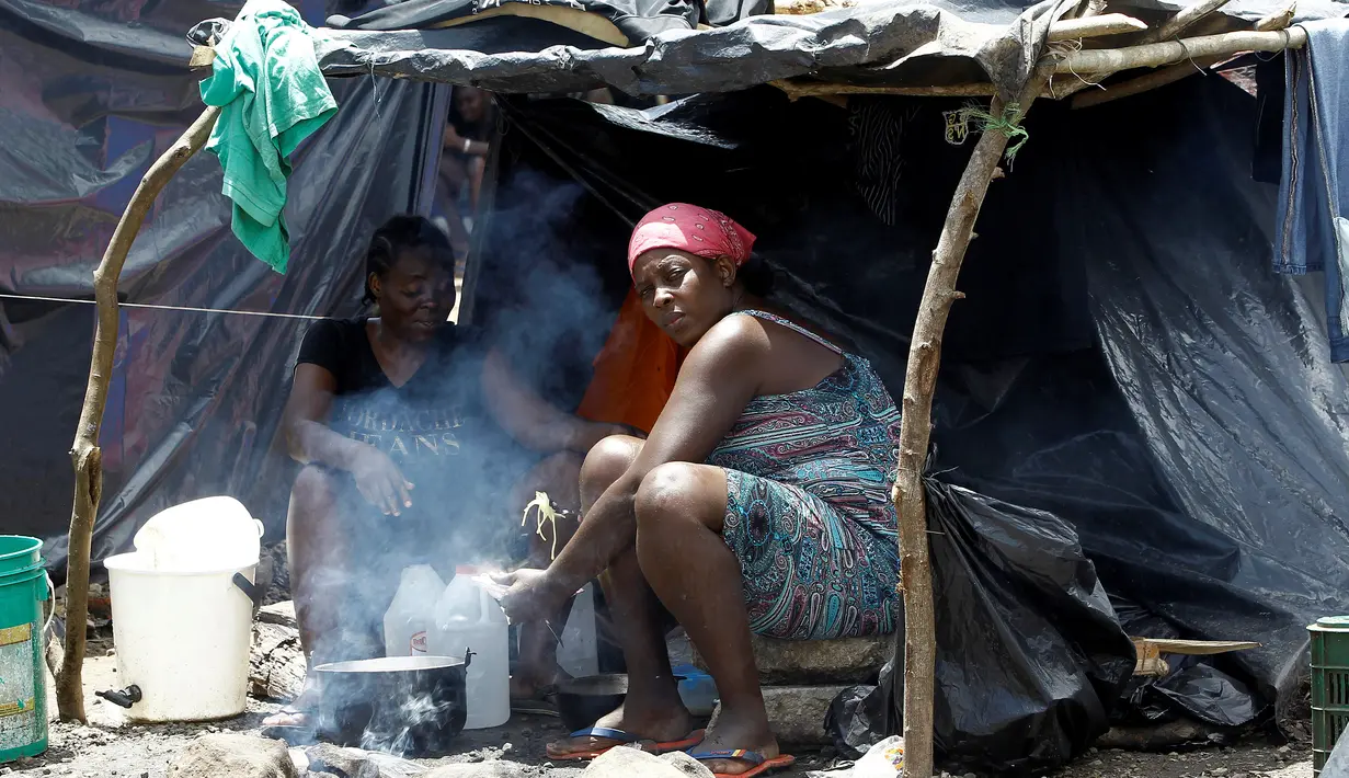 Dua migran Afrika yang terdampar di Kosta Rika memasak makanan di tenda mereka di sebuah kamp darurat di perbatasan antara Kosta Rika dan Nikaragua, di Penas Blancas, Kosta Rika, (14/7). (REUTERS / Juan Carlos Ulate)