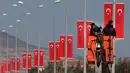 Buruh memasang bendera di tiang listrik menuju perbatasan Oncupinar di Kota Kilis, Turki, Senin (29/1). Bentrokan sempat meletus di puncak bukit strategis di Suriah karena milisi Kurdi mencoba mendapatkan kembali kontrol. (AP Photo/Lefteris Pitarakis)