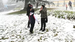 Orang-orang menikmati hujan salju pertama musim ini di Katoomba di pegunungan Blue Mountains, Kamis (10/6/2021). Wilayah ini cenderung memiliki udara yang sejuk dan terkadang sampai turun salju di musim dingin. (AFP/Saeed KHAN)