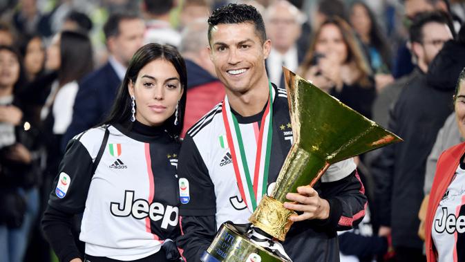 Cristiano Ronaldo bersama kekasihnya, Georgina Rodriguez, berpose dengan trofi Serie A di Stadion Allianz, Turin (19/5/2019). (AFP/Marco Bertorello)
