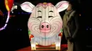 Pengunjung berpose dengan lentera babi yang dipamerkan dalam festival The Great Lanterns of China di Pakruojis Manor, Lithuania, Rabu (25/12/2019). Festival ini berlangsung hingga 6 Januari 2019. (Petras MALUKAS/AFP)