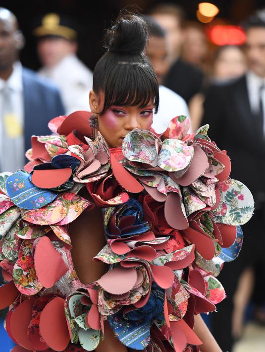 Penampilan Rihanna pada acara penggalangan dana Met Gala 2017 di Metropolitan Museum of Art, New York, Senin (1/5). Rihanna mengenakan busana dengan aksen bunga di sekelilingnya, yang bahannya saling bertumpuk seperti kelopak bunga. (ANGELA WEISS/AFP)