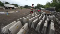 Anak-anak bermain diatas beton di sekitar pembangunan Taman Bersih Manusiawi dan Wibawa (BMW) di Jakarta Utara, Selasa (7/3). Pemprov DKI Jakarta akan melanjutkan kembali pembangunan taman dan stadion BMW. (Liputan6.com/Immanuel Antonius)