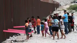 Suasana saat anak-anak bermain jungkat-jungkit yang dipasang di antara pagar pemisah Meksiko dengan Amerika Serikat, Ciudad de Juarez, Meksiko, Minggu (28/7/2019). Jungkat-jungkit tersebut dirancang seorang profesor arsitektur California, Ronald Rael. (AP Photo/Christian Chavez)