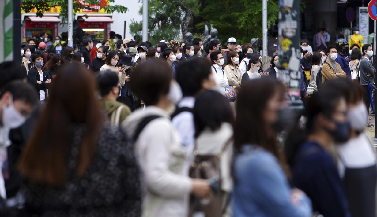 Orang-orang mengenakan masker untuk mencegah virus corona berjalan melintasi penyeberangan pejalan kaki pada awal liburan "Minggu Emas" Jepang di distrik Shibuya, Tokyo, Kamis (29/4/2021). (AP Photo/Eugene Hoshiko)