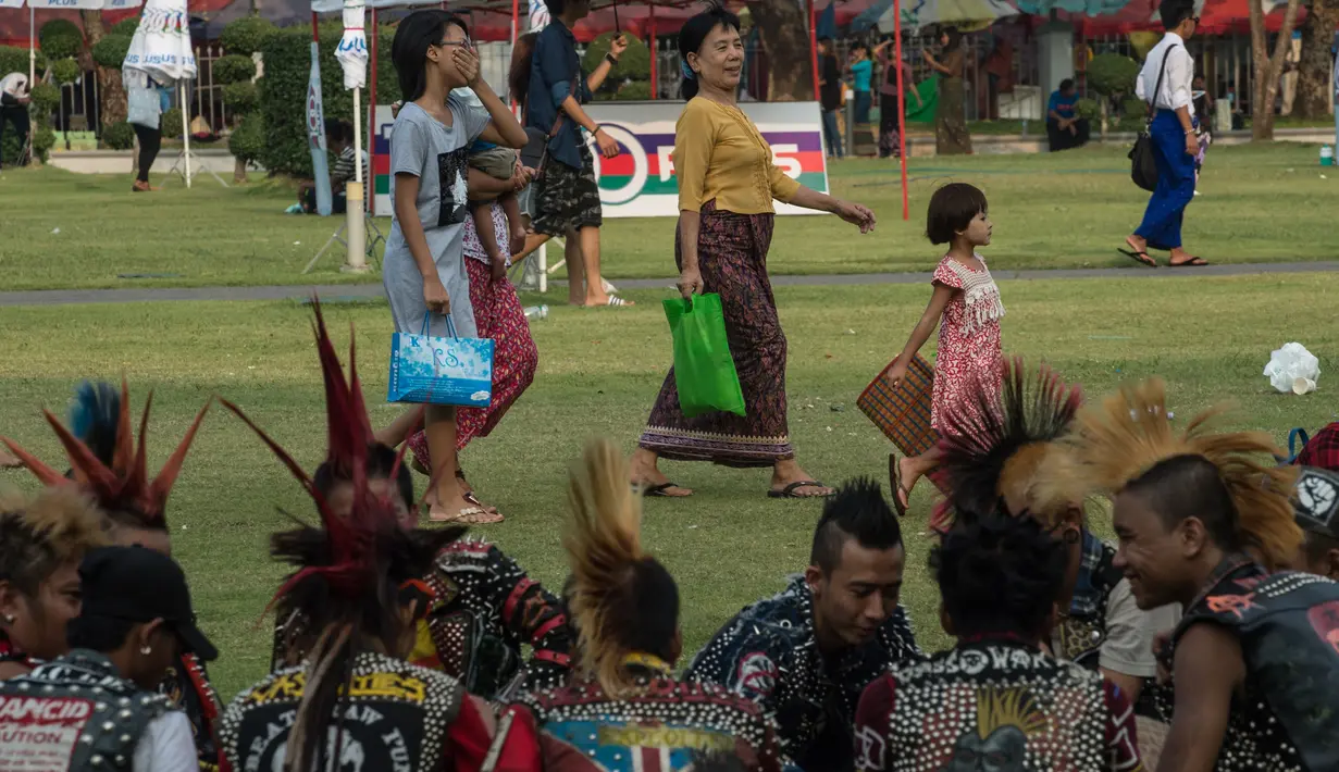 Warga melintas di depan sekelompok anak punk yang berkumpul di sebuah taman di pusat kota Yangon, Myanmar (12/4). Selain Myanmar Empat negara Asia tenggara seperti Thailand, Kamboja dan Laos juga menggelar festival air.  (AFP Photo / Roberto Schmidt)