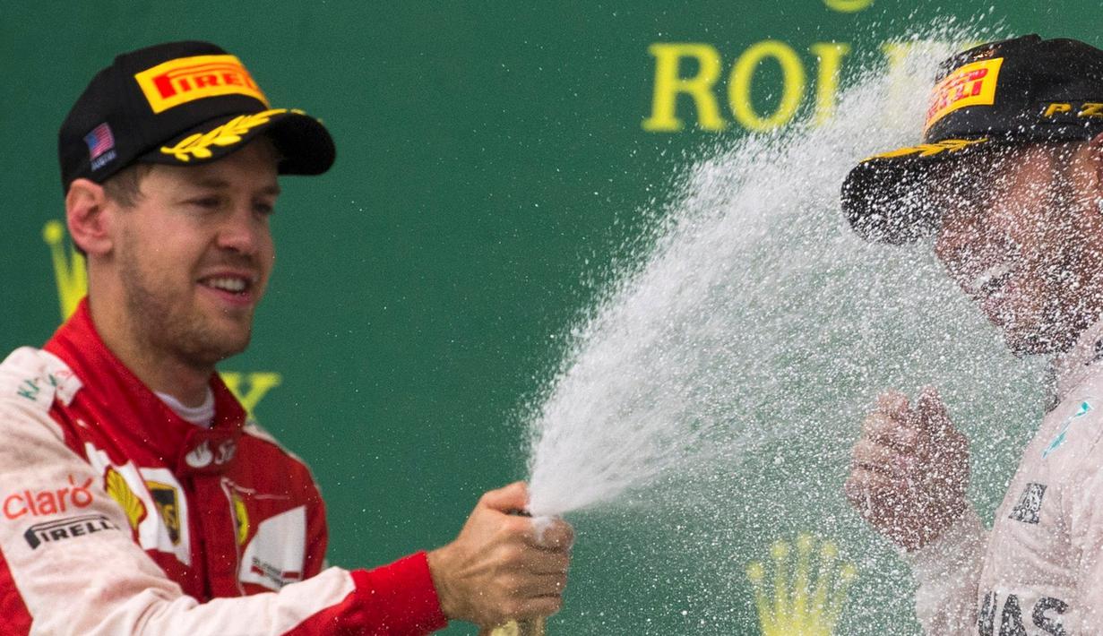 Pebalap Ferrari, Sebastian Vettel, menyemprotkan sampanye ke arah Lewis Hamilton di podium juara F1 GP AS di Sirkuit The Americas, Austin, AS, Senin (26/10/2015) dini hari WIB. (Reuters/Adrees Latif)