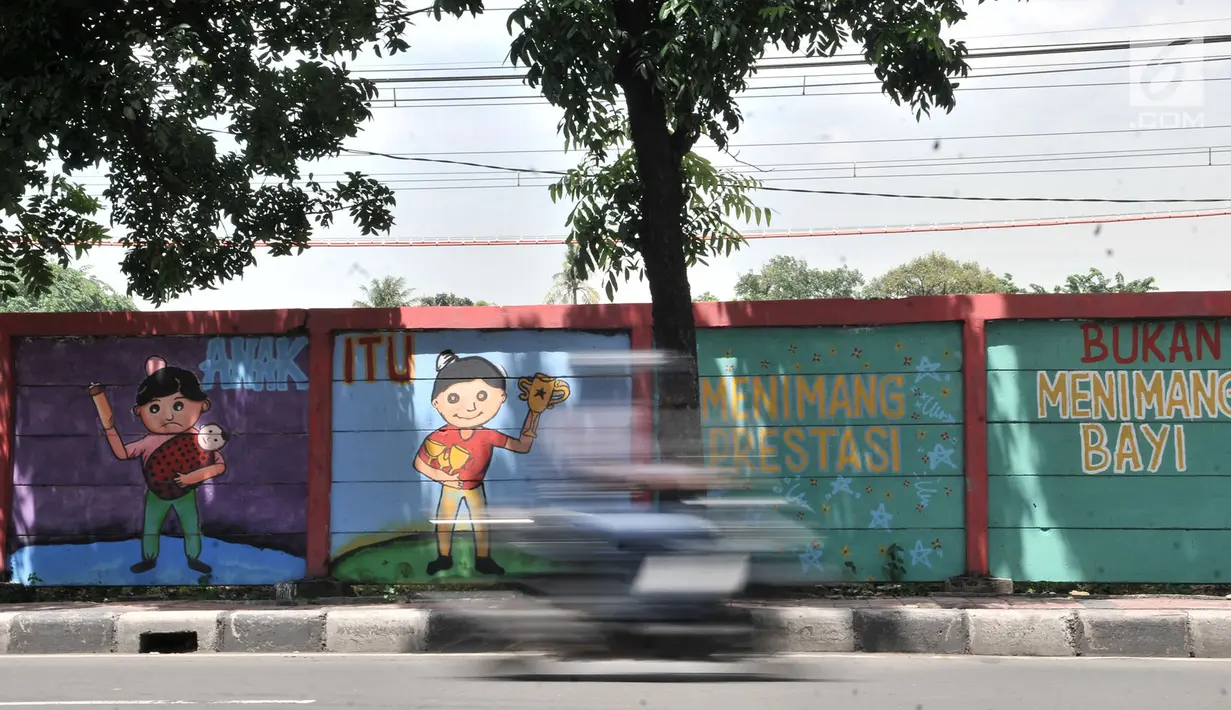 Pengendara melintasi mural bertema 'Tolak Kekerasan Perempuan dan Pelecehan Seksual' di kawasan Jatinegara, Jakarta, Senin (17/12). Mural tersebut juga mengajak masyarakat untuk melindungi kaum perempuan. (Merdeka.com/Iqbal S. Nugroho)