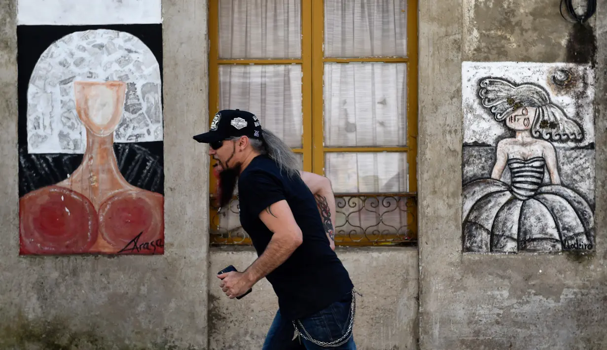 Seorang pria berjalan melewati mural yang terinspirasi oleh karya Velazquez "Las Meninas" selama festival seni jalanan tahunan di Ferrol, Spanyol, Minggu (2/9). Festival ini untuk menghirup kehidupan baru di lingkungan yang sekarat. (MIGUEL RIOPA/AFP)