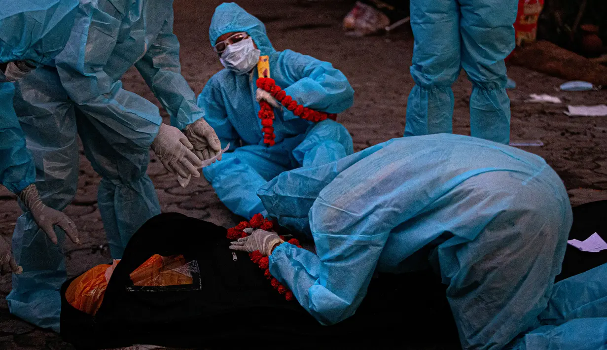 Kerabat dengan mengenakan alat pelindung diri menangis di dekat tubuh saat kremasi seseorang yang meninggal karena virus corona COVID-19 di Gauhati, India pada 28 September 2020. (AP Photo/Anupam Nath)