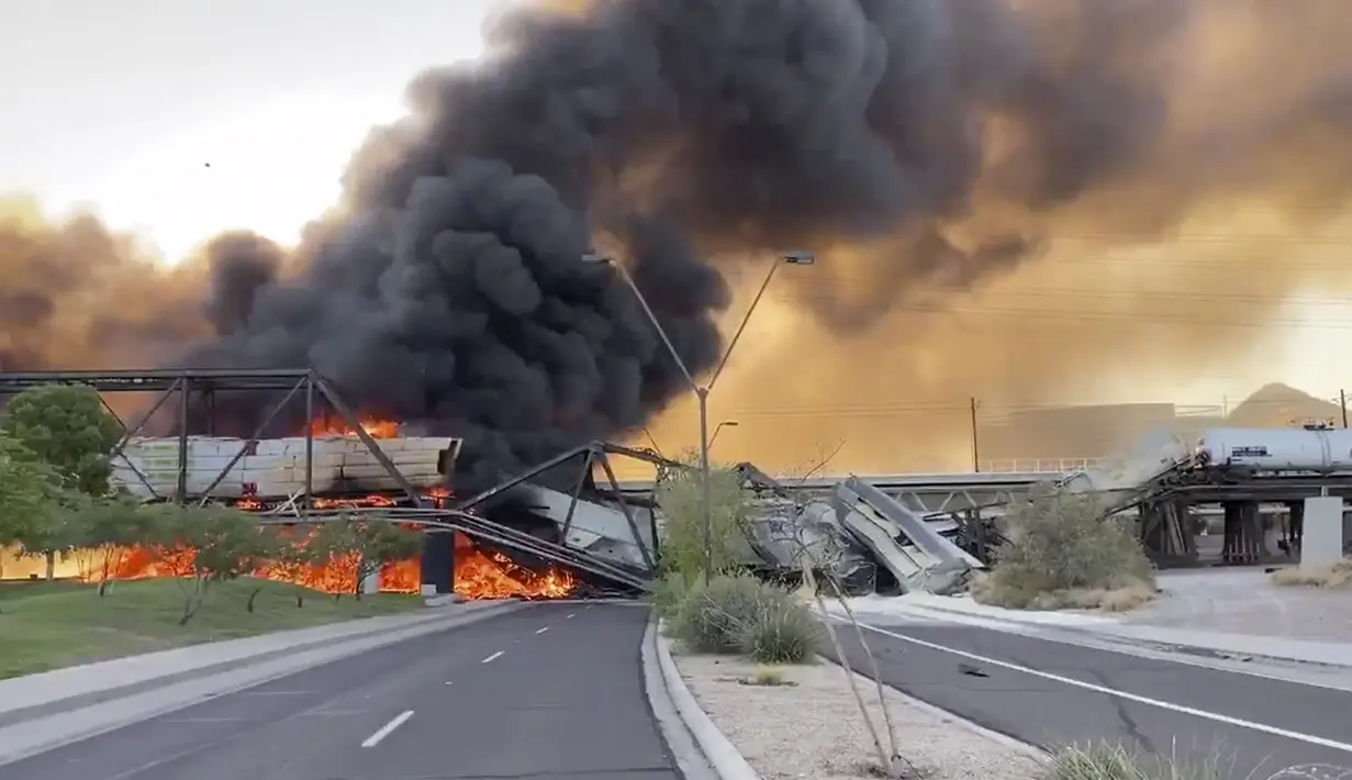 Asap membumbung saat kereta barang tergelincir dan terbakar di jembatan Danau Kota Tempe, Arizona, Amerika Serikat, Rabu (29/7/2020). Tidak ada korban luka dalam kecelakaan yang menurut seorang saksi digambarkan sebagai 'pemandangan neraka' tersebut. (Daniel Coronado via AP)