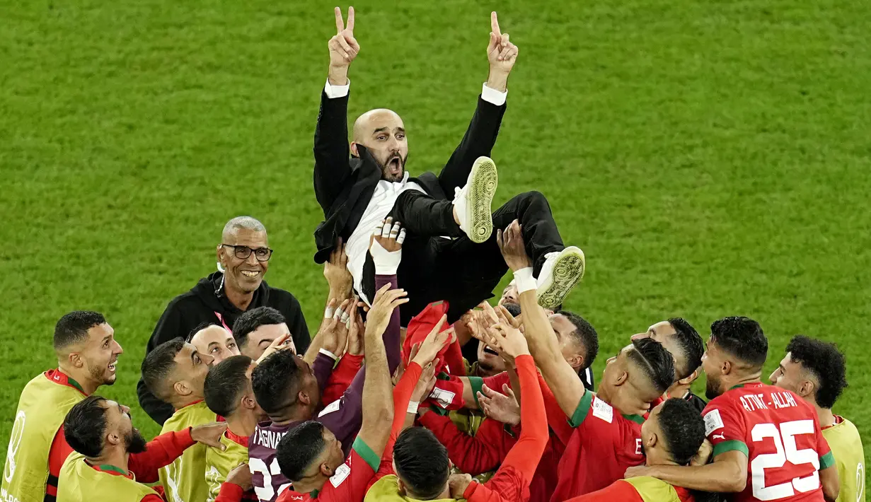 Para pemain Maroko mengangkat pelatih Walid Regragui saat merayakan kemenangan atas Spanyol pada laga 16 besar Piala Dunia 2022 di Stadion Education City, Selasa (6/12/2022). (AP/Abbie Parr)