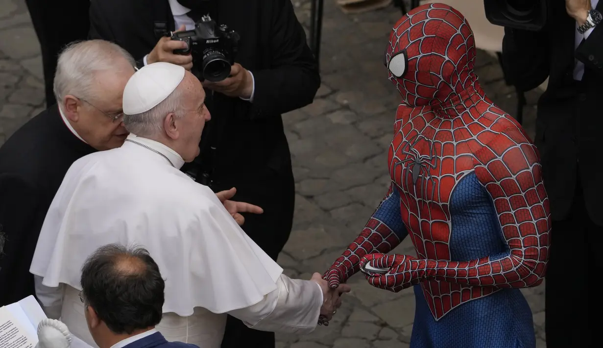 Paus Fransiskus bertemu Spider-Man, yang memberinya masker, pada akhir audiensi umum mingguan dengan jumlah umat terbatas di San Damaso Courtyard, Vatikan, Rabu (23/6/2021). Pria itu adalah Mattia Villardita (27) dari Italia utara yang menghibur anak-anak di rumah sakit. (AP Photo/Andrew Medichini)