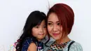 Cici Panda tampil fresh dengan tatanan rambut yang dipotong pendek dan diwarnai dengan cat rambut berwarna coklat kemerahan. Ia menggendong kesayangannya yaitu Alika yang tampak bersender manja dengan sang mama. (Andy Masela/Bintang.com)