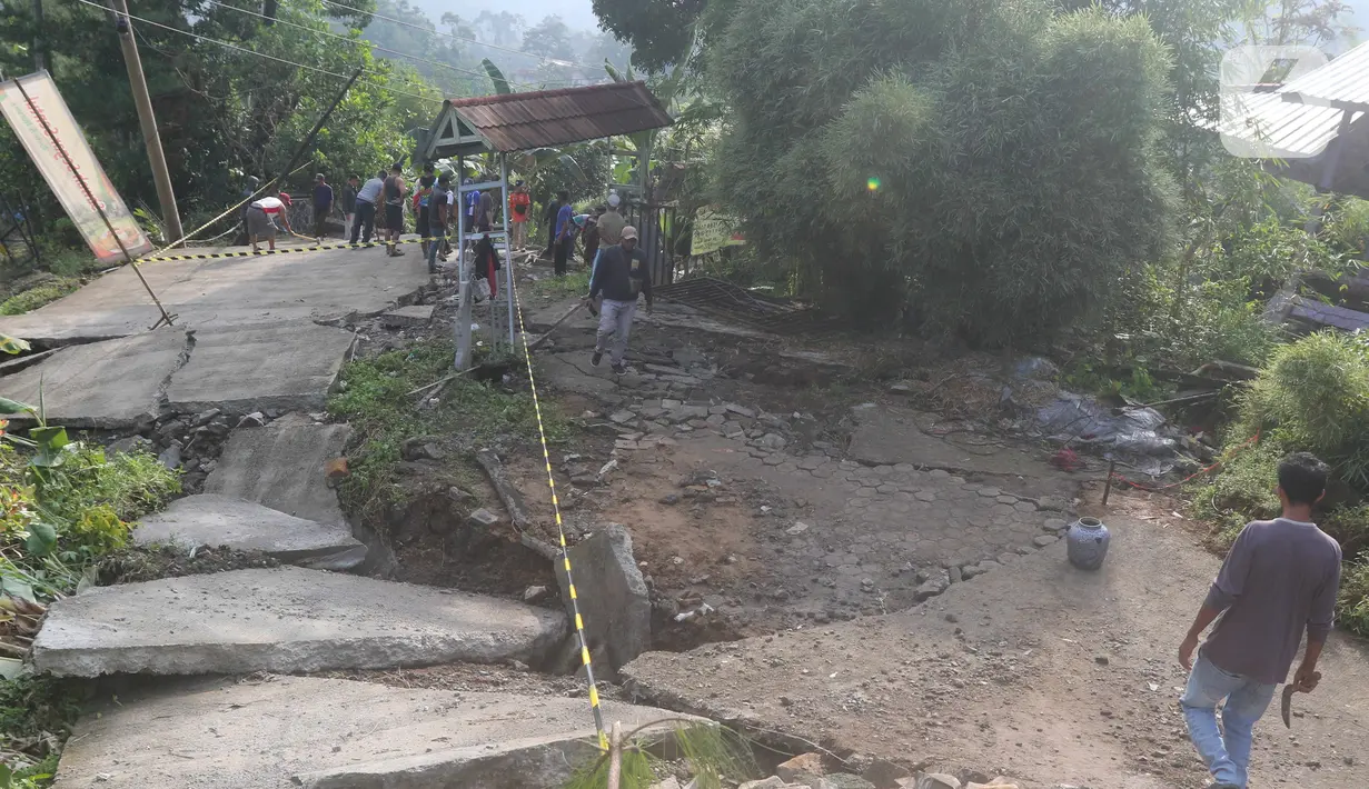 Kondisi jalan yang terbelah akibat pergeseran tanah di kawasan Bojong Koneng, Babakan Madang, Kabupaten Bogor, Jawa Barat, Jumat (16/9/2022). Badan Penanggulangan Bencana Daerah (BPBD) setempat mencatat 18 unit rumah mengalami kerusakan, dan pergeseran tanah itu menyebabkan retakan-retakan di tanah, dinding, plafon dan lantai rumah warga serta akses jalan sudah tidak bisa dilewati oleh kendaraan roda dua dan roda empat. (Liputan6.com/Herman Zakharia)
