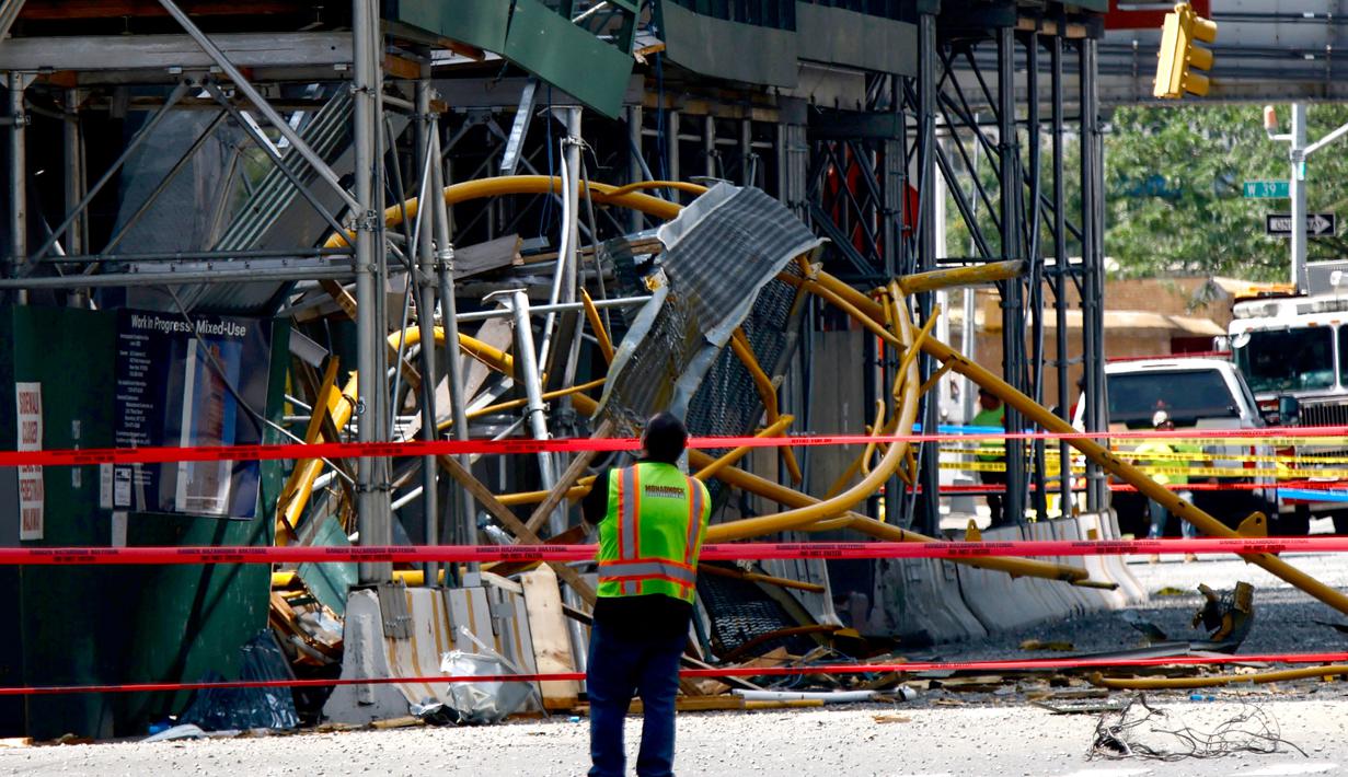 Seorang pekerja melihat ke atas di lokasi kebakaran dan runtuhnya derek konstruksi di New York, pada Rabu (26/7/2023). Dua belas orang, termasuk sembilan warga sipil dan tiga petugas pemadam kebakaran, semuanya menderita luka-luka yang tidak mengancam jiwa setelah sebuah derek jatuh di New York City pada hari Rabu. (Kena Betancur / AFP)