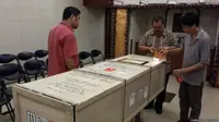 Dua staf KJRI Hong Kong menyaksikan penyegelan peti kargo berisi peti jenazah Wiji Astutik Supardi untuk dikirim pulang. (BBC Indonesia)