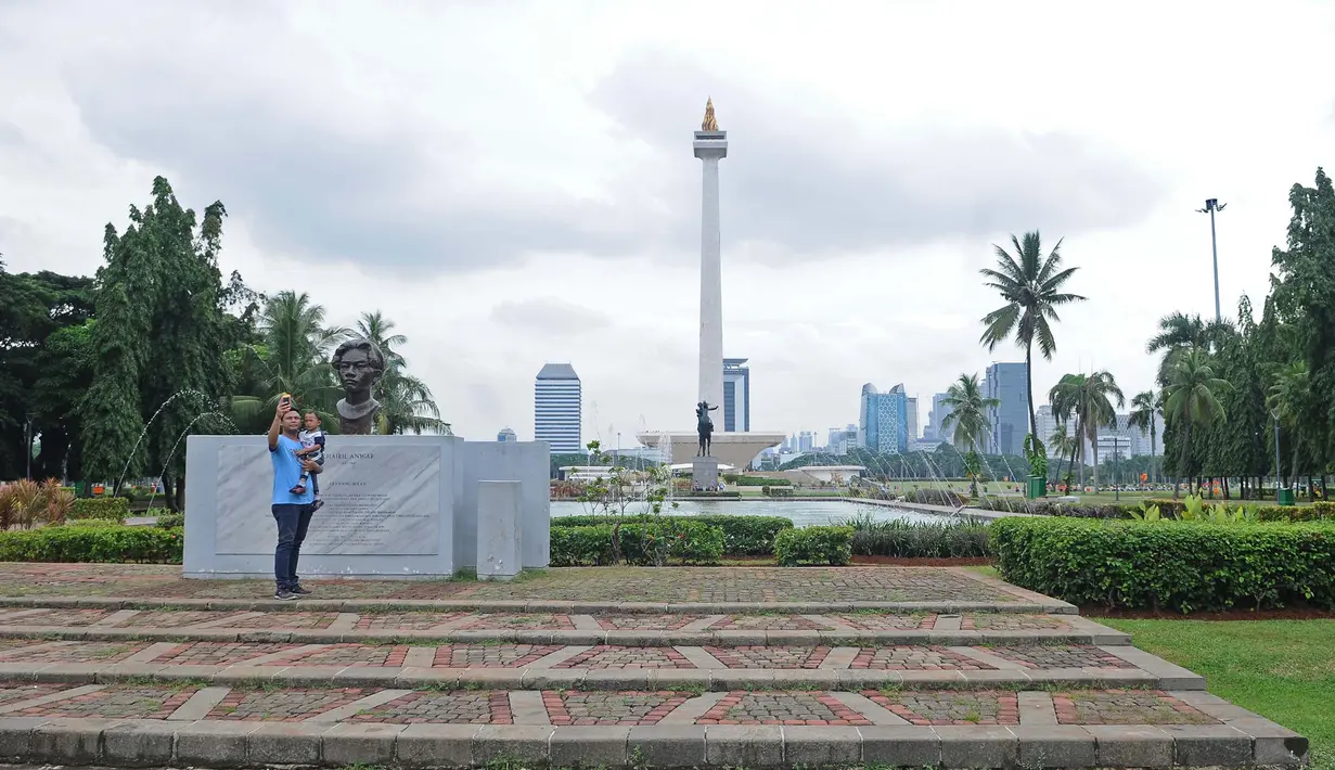 Pengunjung berswafoto dengan latar belakang pemandangan Monas, Jakarta, Rabu (23/1). Penataan ulang sejumlah taman di kawasan Monas untuk mempercantik kawasan tersebut. (Liputan6.com/Herman Zakharia)