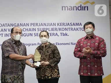 Direktur Commercial Banking Bank Mandiri Riduan (kedua kiri) memberikan cinderamata kepada Komisaris Utama Inti Bangun Sejahtera Farida Bau pada acara perjanjian kerjasama pembiayaan rekanan sebesar Rp250 miliar pada tahap awal di Jakarta, Selasa (22/12/2020). (Liputan6.com/HO/Wedi)