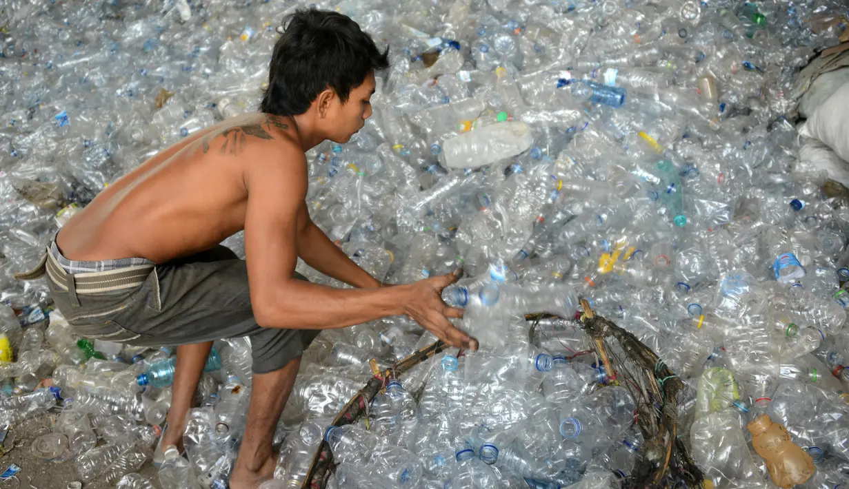 Pengumpul sampah memilih botol plastik di sebuah gudang sampah di Nusa Dua, di pulau resor Indonesia Bali (2/5). (AFP Photo/Sonny Tumbelaka)