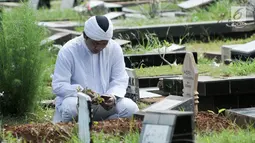 Umat Muslim membaca doa di depan pusara makam di Tempat Pemakaman Umum (TPU) Karet Bivak, Jakarta, Minggu (25/6). Hari pertama Lebaran, sejumlah warga memadati TPU untuk melangsungkan tradisi ziarah usai salat Idul Fitri. (Liputan6.com/Yoppy Renato)
