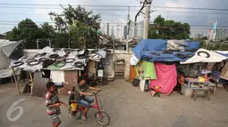 Sejumlah anak bersepeda melewati gubuk liar yang didirikan di jalur inspeksi KBB, Kebon Melati, Jakarta, Rabu (1/6). Meski berulang kali ditertibkan, warga tak jera untuk kembali membangun gubuk liar di kawasan tersebut. (Liputan6.com/Immanuel Antonius)