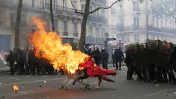 Pengunjuk rasa mendorong troli yang terbakar ke arah polisi anti huru hara Prancis selama demonstrasi perayaan May Day di Paris,Senin (1/5). Hari Buruh Internasional di Paris, diwarnai bentrokan antara pengunjuk rasa dengan polisi. (Zakaria ABDELKAFI/AFP)