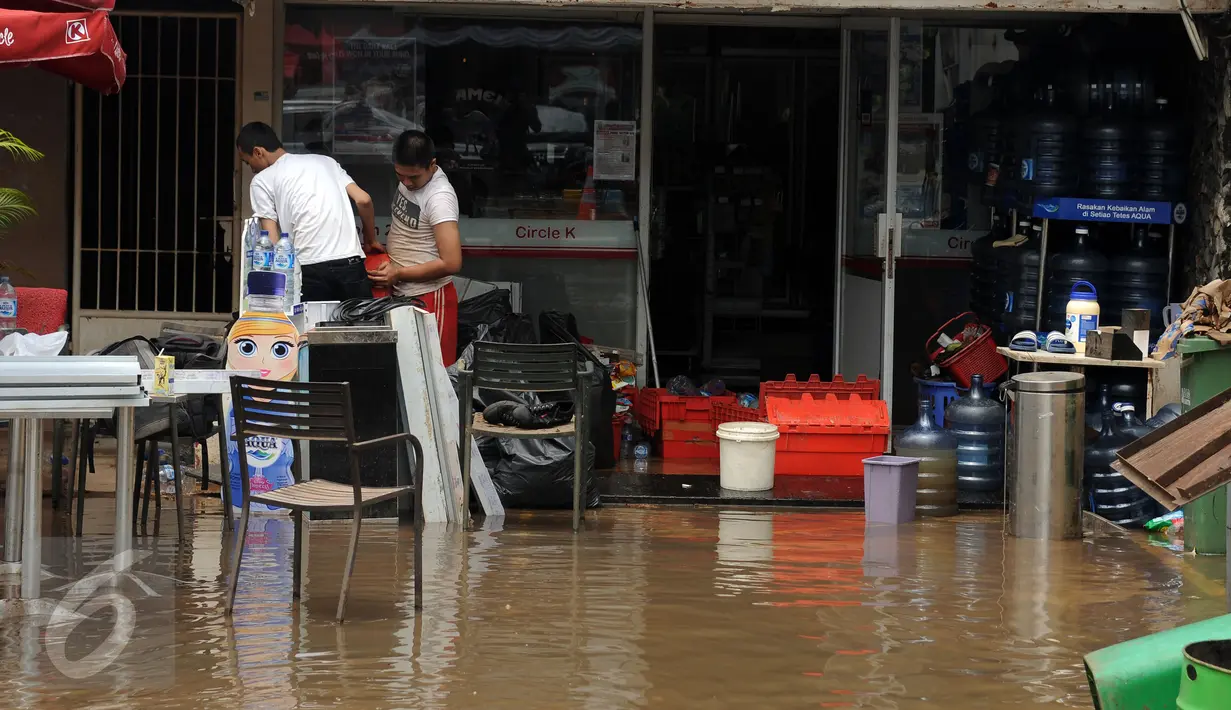 Beberapa karyawan memindahkan barang usai banjir di Jalan Kemang Raya, Minggu (28/8). Sejumlah kendaraan terendam air di kawasan Kemang Raya pasca hujan deras di Jakarta pada Sabtu (27/8). (Liputan6.com/Helmi Fithriansyah)