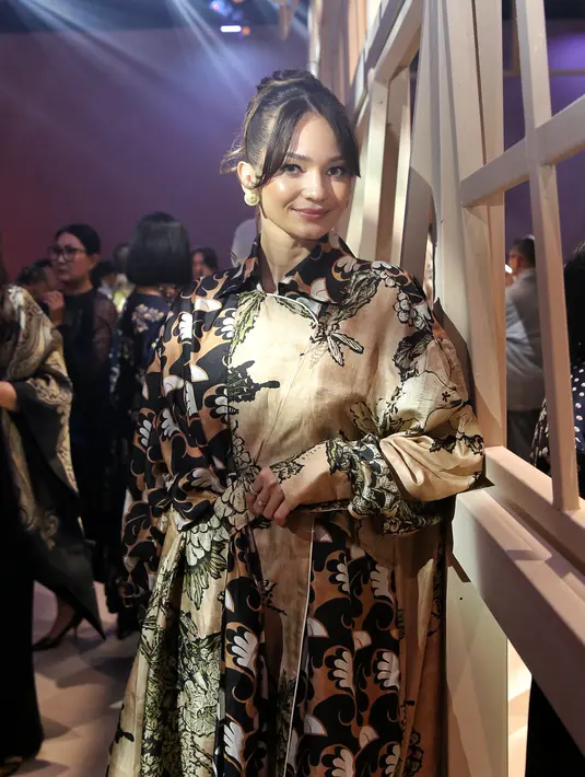 Enzy Storia tampil cantik saat menghadiri gelaran BIYAN SS25 'Fleur.' Ia mengenakan dress berkerah bernuansa cokelat keemasan dengan aksen tumpuk yang manis, rancangan Biyan. [Foto: Document FIMELA/Adrian Putra]