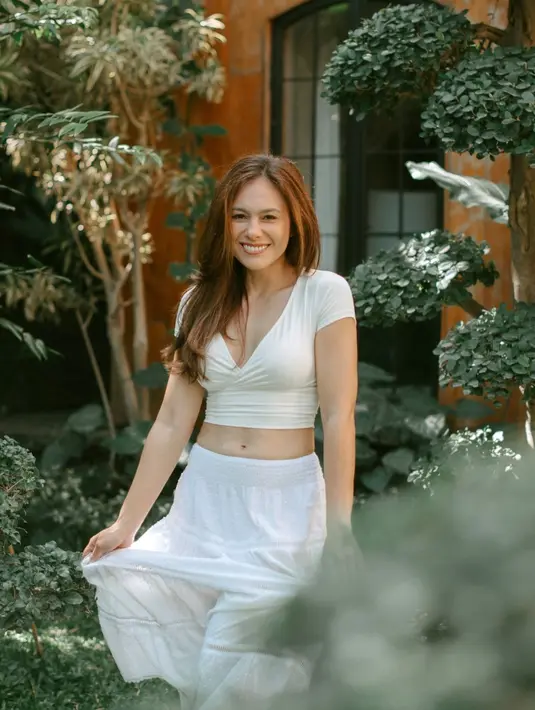 Wulan Guritno tampil dengan gaya bohemian mengenakan crop top. V-neck crop top berwarna putih itu dipadukan dengan rok panjang berwarna senada. [instagram/wulanguritno]