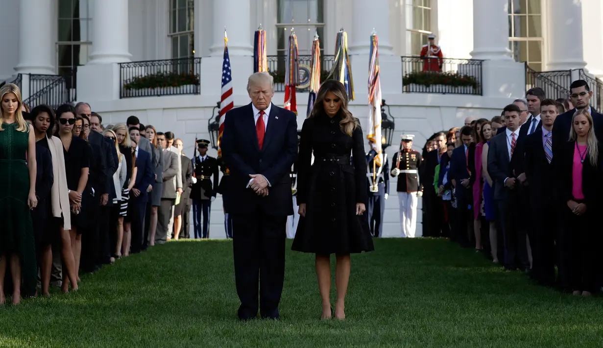 Presiden AS Donald Trump dan Ibu Negara, Melania Trump mengheningkan cipta untuk korban serangan 11 September 2001 dalam acara peringatan di Gedung Putih, Senin (11/9). Trump untuk pertama kalinya sebagai Presiden memimpin peringatan 9/11. (AP/Evan Vucci)