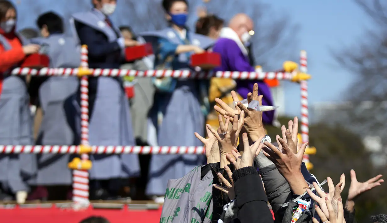 Orang-orang mencoba menangkap kacang keberuntungan yang disebarkan pada "Mame-maki," upacara pelemparan kacang di kuil Buddha Zojoji di Tokyo, 3 Februari 2022. Ritual yang diyakini membawa keberuntungan dan mengusir kejahatan dilakukan setiap tahun untuk menandai awal musim semi. (AP/Eugene Hoshiko)