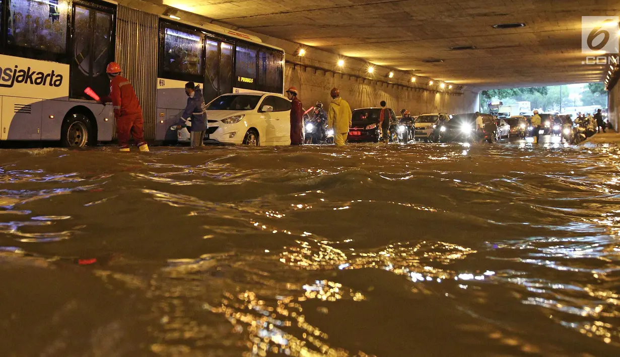 Petugas mengatur arus lalu lintas saat banjir melanda underpass Cawang, Jalan MT Haryono, Jakarta, Selasa (12/12). Hujan deras dan buruknya drainase di kawasan ini menjadi penyebab utama adanya genangan air hingga 50 cm. (Liputan6.com/Herman Zakharia)