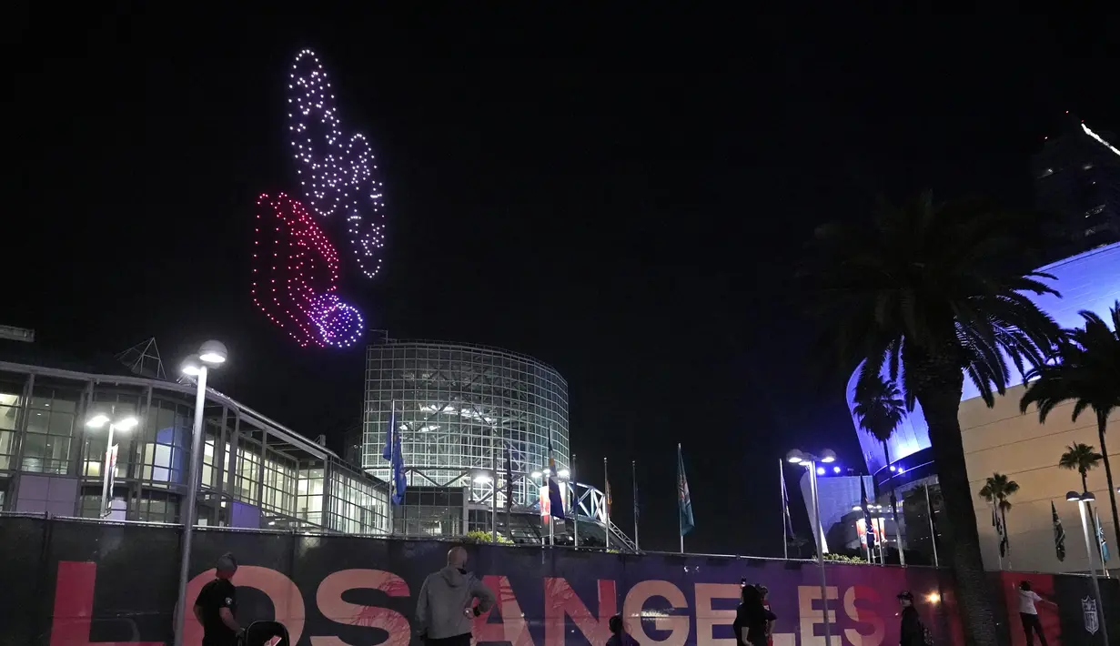 Pecinta olahraga menyaksikan 500 drone terbang membentuk kamera film saat Super Bowl LVI Drone Show di atas Los Angeles Convention Center, California, AS, 11 Februari 2022. The Rams dijadwalkan bertanding melawan Cincinnati Bengals dalam Super Bowl pada 13 Februari 2022. (AP Photo/Damian Dovarganes)