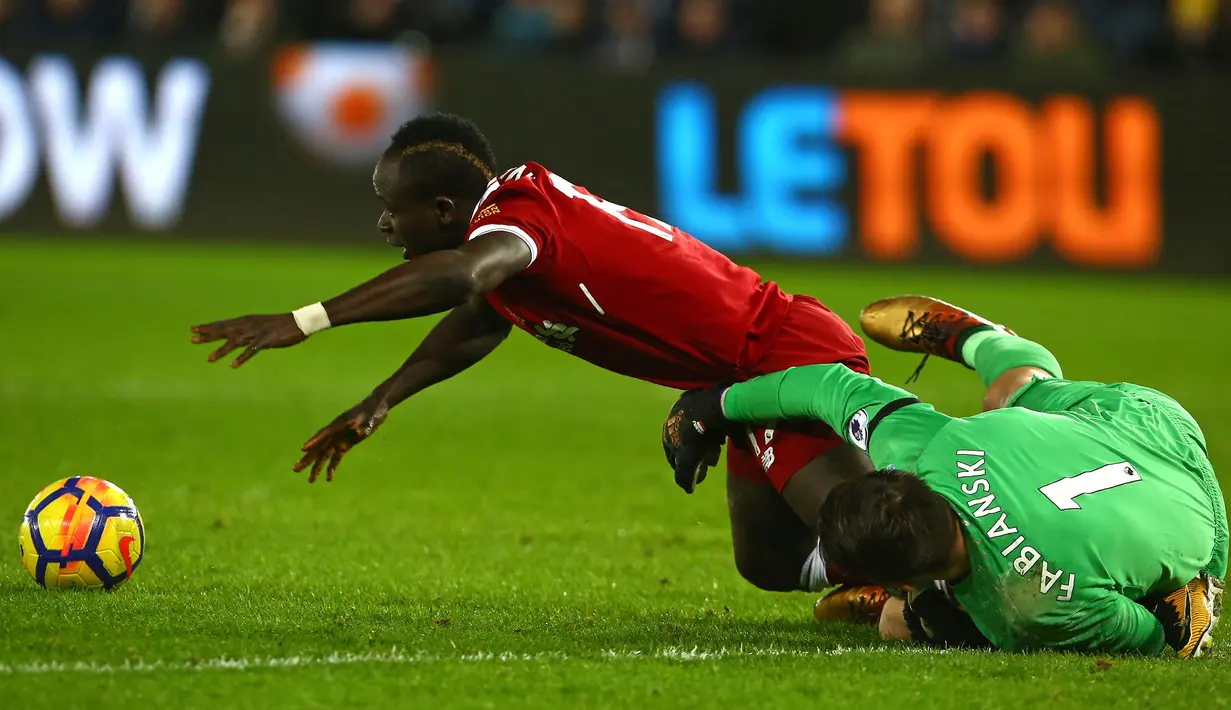 Gelandang Liverpool, Sadio Mane dihalangi oleh kiper Swansea City, Lukasz Fabianski dalam lanjutan Premier League di Stadion Liberty, Selasa (23/1). Swansea City menjadi penjegal Liverpool meneruskan rekor tanpa kalah. (Geoff CADDICK/AFP)