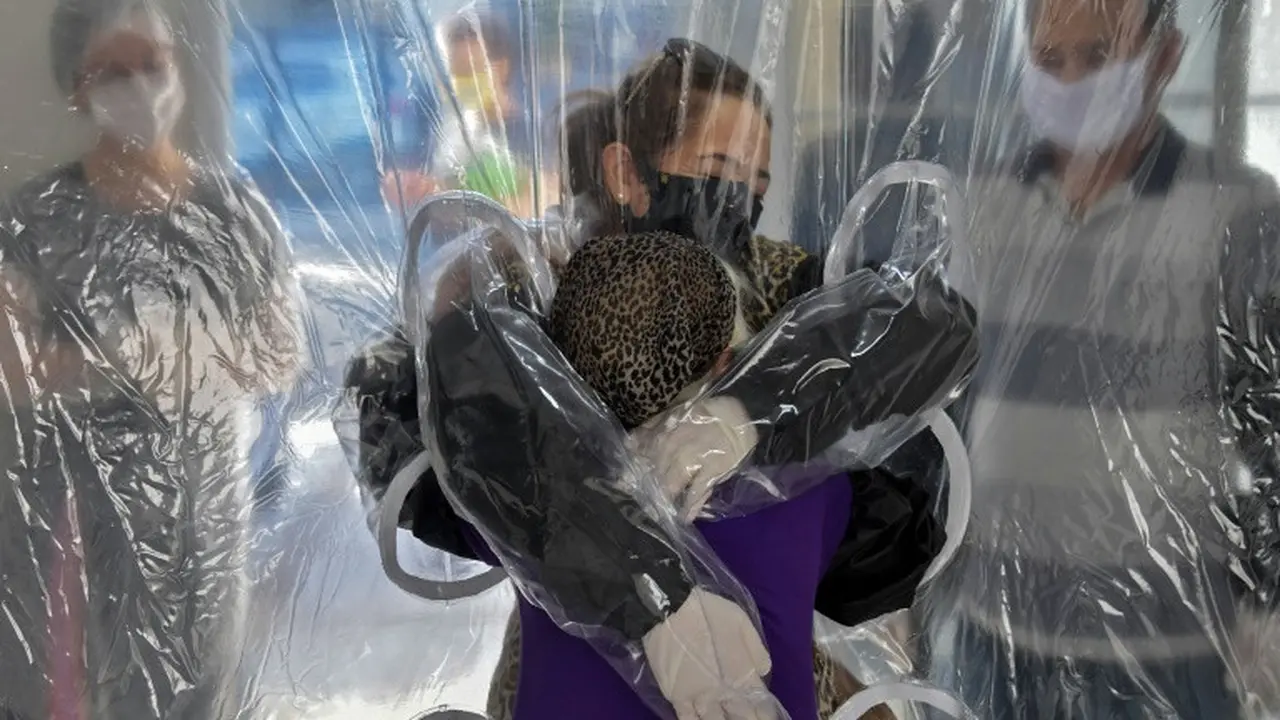 Suasana haru saat Elisabete Nagata memeluk adik iparnya yang berusia 76 tahun, Luiza Nagata, melalui tirai plastik transparan di suatu panti jompo di Sao Paulo, Brasil, pada 13 Juni 2020. (Photo Credit: AFP/ NELSON ALMEIDA)