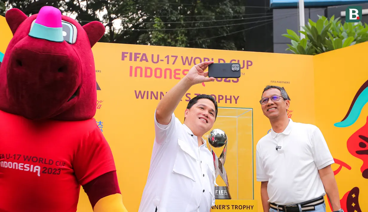 <p>Ketua PSSI, Erick Thohir (tengah), melakukan swafoto bersama Penjabat (Pj) Gubernur DKI Jakarta, Heru Budi Hartono (kanan), saat memamerkan trofi Piala Dunia U-17 2023 kepada masyarakat di Bundaran Hotel Indonesia (HI), Jakarta, Minggu (15/10/2023). (Bola.com/Bagaskara Lazuardi)</p>